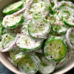 Creamy cucumber salad served in a bowl with fresh herbs and spices