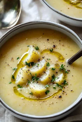 A warm bowl of creamy potato leek soup garnished with fresh herbs.