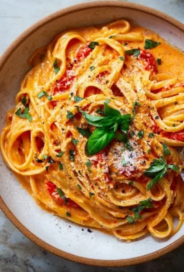 Bowl of creamy tomato pasta garnished with fresh basil and parmesan cheese