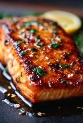 Crispy honey garlic glazed salmon served on a plate with herbs and lemon.