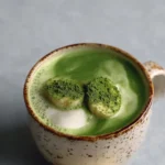 Creamy banana cream matcha latte in a glass garnished with banana slices.