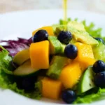 Mango cucumber salad with blueberries and avocado on a plate.