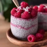 Delicious raspberry chia pudding in a clear glass topped with fresh raspberries