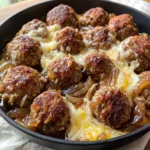Dish of French Onion Meatballs topped with melted cheese and caramelized onions.