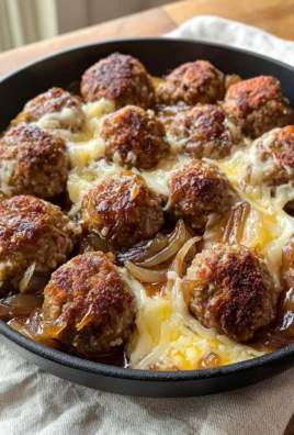 Dish of French Onion Meatballs topped with melted cheese and caramelized onions.