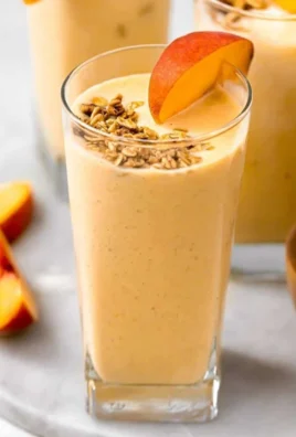Banana Peach Protein Smoothie in a glass with fruits on the side