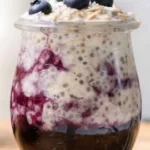 Bowl of blueberry overnight oats topped with fresh blueberries and nuts.