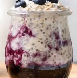 Bowl of blueberry overnight oats topped with fresh blueberries and nuts.