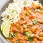 Bowl of creamy vegan Coconut Chickpea Curry topped with fresh herbs.