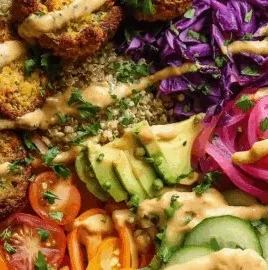 Falafel power bowl with quinoa, fresh veggies, and spicy harissa sauce.