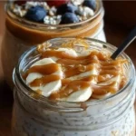 High protein overnight oats topped with fruits and nuts in a glass bowl.