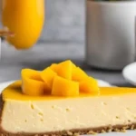 Delicious slice of Mango Cheesecake garnished with fresh mangoes.