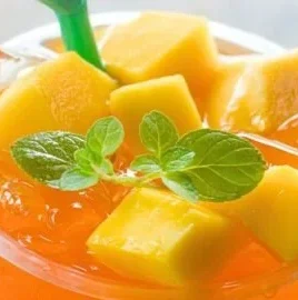 Refreshing glass of mango iced tea served with ice and mint leaves