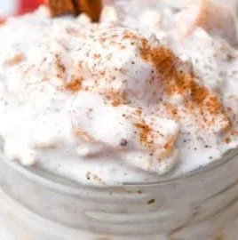 Bowl of Peaches & Cream Overnight Oats topped with fresh peaches and nuts.