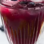 A cup of blueberry-lemon green tea with fresh blueberries and lemon slices.