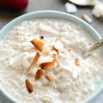 Bowl of tasty coconut cream oats topped with fruits and nuts.
