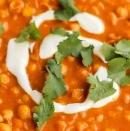 Bowl of vegan chickpea curry with spices and herbs, served with rice.