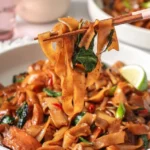 Plate of drunken noodles with colorful vegetables and herbs