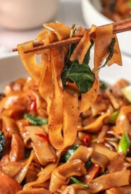 Plate of drunken noodles with colorful vegetables and herbs