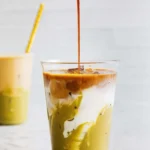 Iced Pistachio Latte in a glass with a straw and pistachio garnish
