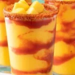 A vibrant Mangonada beverage made with mango, chili, and lime in a clear glass.