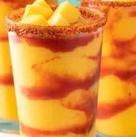 A vibrant Mangonada beverage made with mango, chili, and lime in a clear glass.