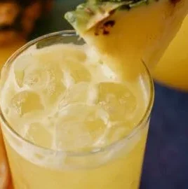 Refreshing Pineapple Cooler drink in a glass garnished with fresh pineapple slices.