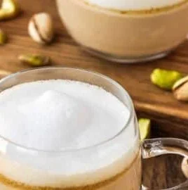 Delicious pistachio latte topped with cream and nuts in a coffee cup