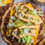 Smash burger tacos garnished with fresh toppings on a wooden serving platter