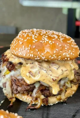 Delicious smash burgers topped with baconnaise sauce on a wooden plate.