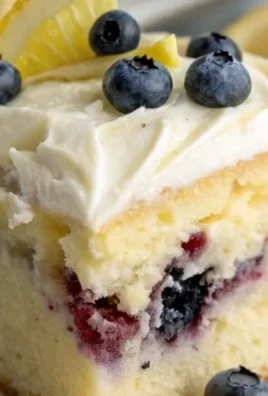 Blueberry lemon poke cake topped with fresh blueberries and lemon zest