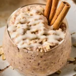 Bowl of cinnamon roll overnight oats topped with cinnamon and nuts