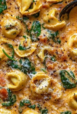 Creamy spinach tomato tortellini served in a bowl garnished with herbs