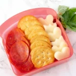 DIY Pizza Crackers Lunchable with cheese, pepperoni, and dipping sauce.