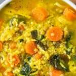 Bowl of Lemon Turmeric Chicken Soup garnished with herbs.