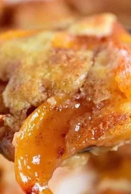 A golden-brown peach cobbler baked to perfection, topped with fresh peaches.