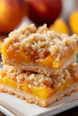 Freshly baked Peach Crumb Bars, topped with a golden crumb layer and juicy peach filling