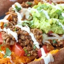 Delicious taco stuffed sweet potatoes topped with fresh ingredients and garnishes.